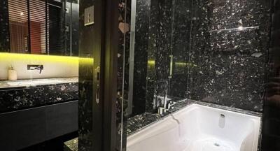 Modern bathroom with dark marble design, bathtub, and vanity