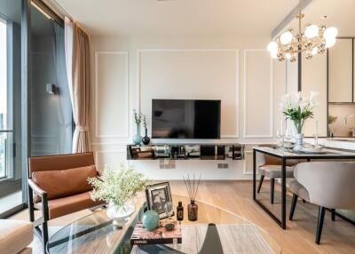 Modern living room with a large TV, a comfortable seating area, and a partial view of the kitchen