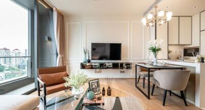 Modern living room with a large TV, a comfortable seating area, and a partial view of the kitchen