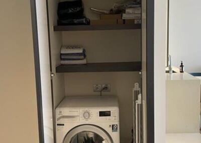 Stacked washer in an open utility closet with shelves