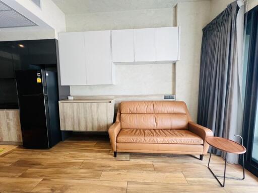 Living area with a brown leather sofa, modern cabinets, and a large fridge