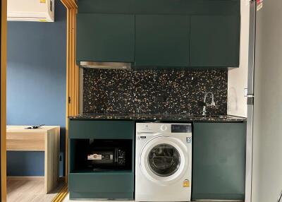 Compact modern kitchen with washing machine and dark green cabinets