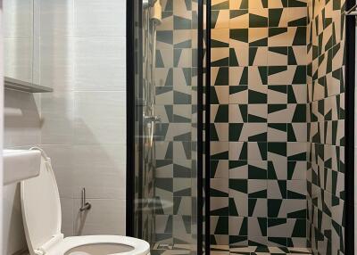 Modern bathroom with geometric tiled shower and white toilet