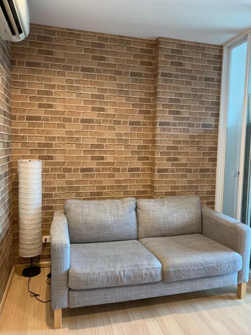Cozy living room with a gray sofa and brick wall