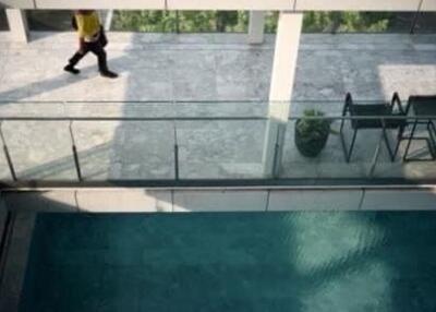 View of pool area with person walking on upper floor