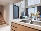 Modern kitchen with a view of the living area featuring a high ceiling and large windows.