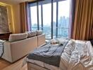 Modern bedroom with a city view, featuring a bed, a sofa, and large windows.