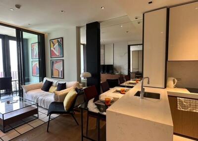 Modern open-plan living room with kitchen and dining area featuring large windows and balcony.