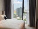 Modern bedroom with a large window offering a panoramic city view