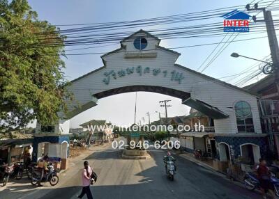 Entrance to a residential area with arched gateway and visible contact information