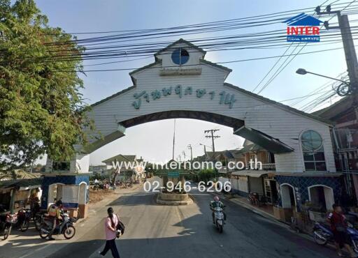 Entrance to a residential area with arched gateway and visible contact information