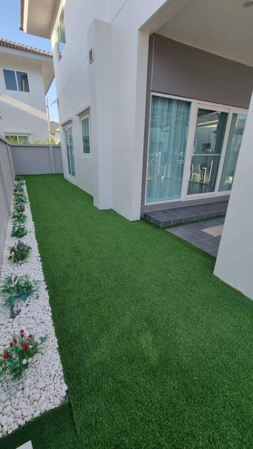 Modern outdoor area with artificial grass and flower bed