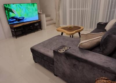 Modern living room with grey couch, large TV, and wooden coffee table