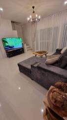 Modern living room with grey couch, large TV, and wooden coffee table