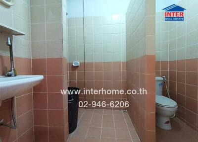 Bathroom with tiled walls and floor, toilet, sink, and shower area