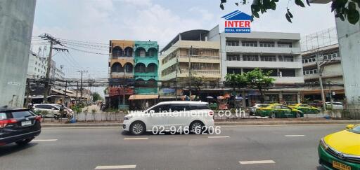 Street view of buildings with vehicles on road and real estate sign