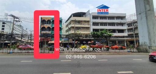 Exterior shot of multiple buildings along a main road with visible traffic and a real estate sign