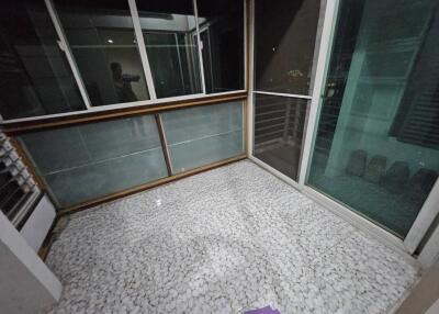 Spacious enclosed balcony with sliding glass doors and pebble-tiled floor