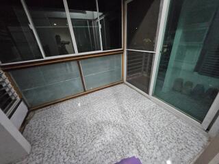 Spacious enclosed balcony with sliding glass doors and pebble-tiled floor