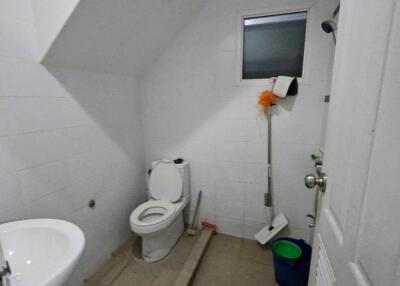Bathroom with a toilet, washbasin, small window, and cleaning equipment