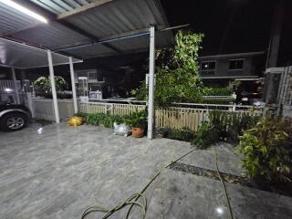 Covered outdoor area with plants and parked car