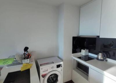 Modern kitchen with white cabinets, washing machine, and appliances