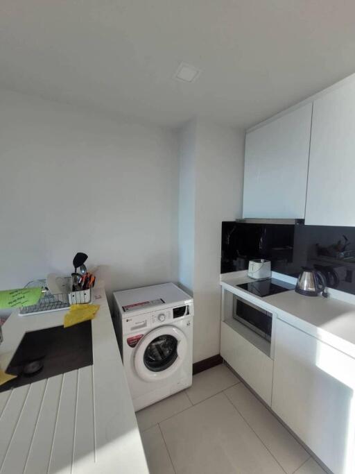 Modern kitchen with white cabinets, washing machine, and appliances