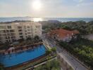 Overhead view of an apartment complex and pool with a view of the ocean in the background