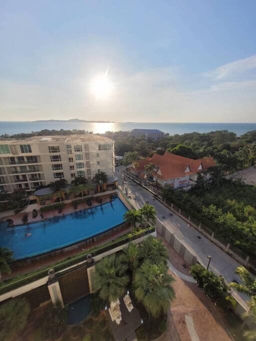 Overhead view of an apartment complex and pool with a view of the ocean in the background