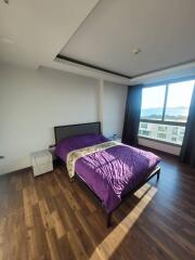 Modern bedroom with wooden flooring and a large window