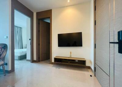 Modern living area with wall-mounted TV and adjacent bedroom.