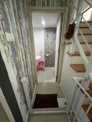 Small bathroom accessed via narrow hallway with stairs