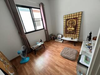 Small bedroom with wooden flooring, window, and various decorations