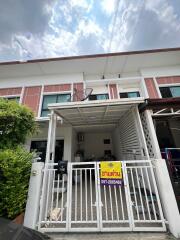 Front view of a residential building with a gated entrance and a for-sale sign