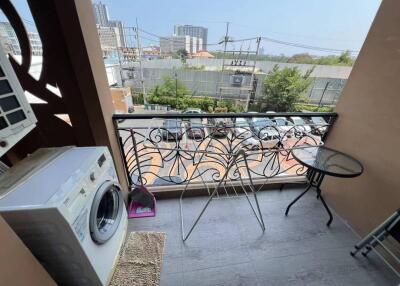 A balcony with a washing machine, table, and city view.