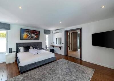 Modern bedroom with large bed, wall-mounted TV, large window, and ensuite bathroom