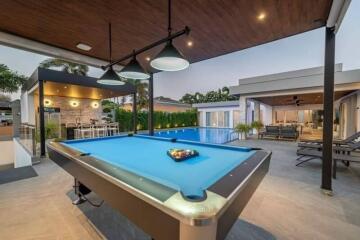 Outdoor entertainment space with a pool table, swimming pool, and seating area