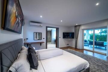 Spacious bedroom with large bed, wall art, TV, and access to outdoor area