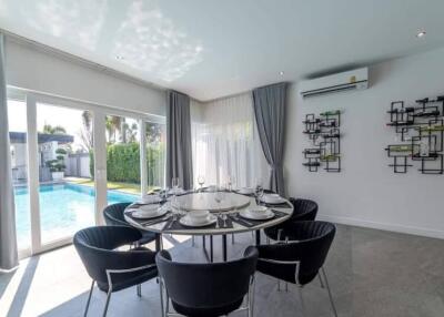 Modern dining area with round table and pool view
