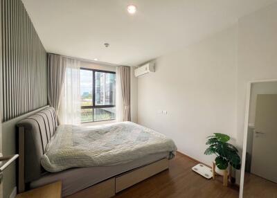 Spacious bedroom with large window, bed, air conditioner, and wooden flooring