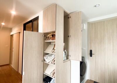 Open storage cabinet with shoes and miscellaneous items at entrance area