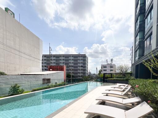 Outdoor pool with lounge chairs and buildings in the background