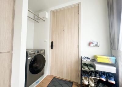 Entryway with washer, shoe rack, and light wood door