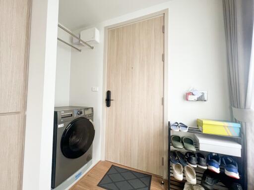 Entryway with washer, shoe rack, and light wood door