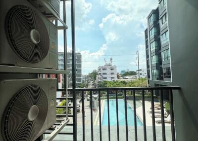 Balcony view overlooking a swimming pool with adjacent high-rise buildings and air conditioning units