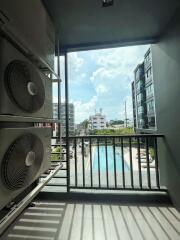 Balcony view overlooking a swimming pool with adjacent high-rise buildings and air conditioning units