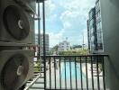 Balcony view overlooking a swimming pool with adjacent high-rise buildings and air conditioning units