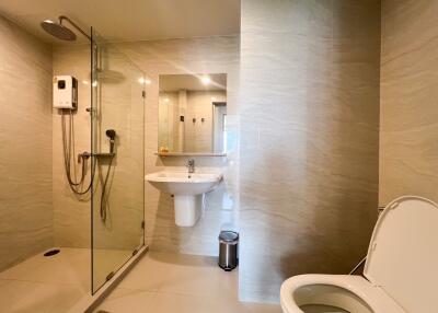 Modern bathroom with glass shower enclosure, wall-mounted sink, and toilet