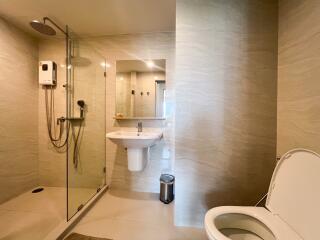 Modern bathroom with glass shower enclosure, wall-mounted sink, and toilet