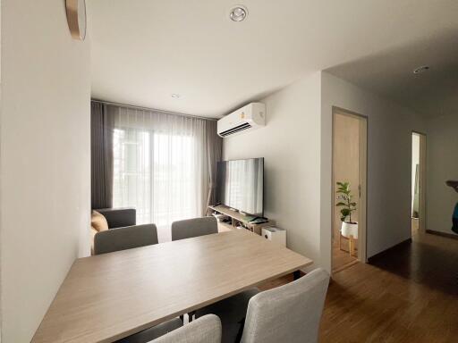 Modern living room with dining table, TV, and large window with curtains